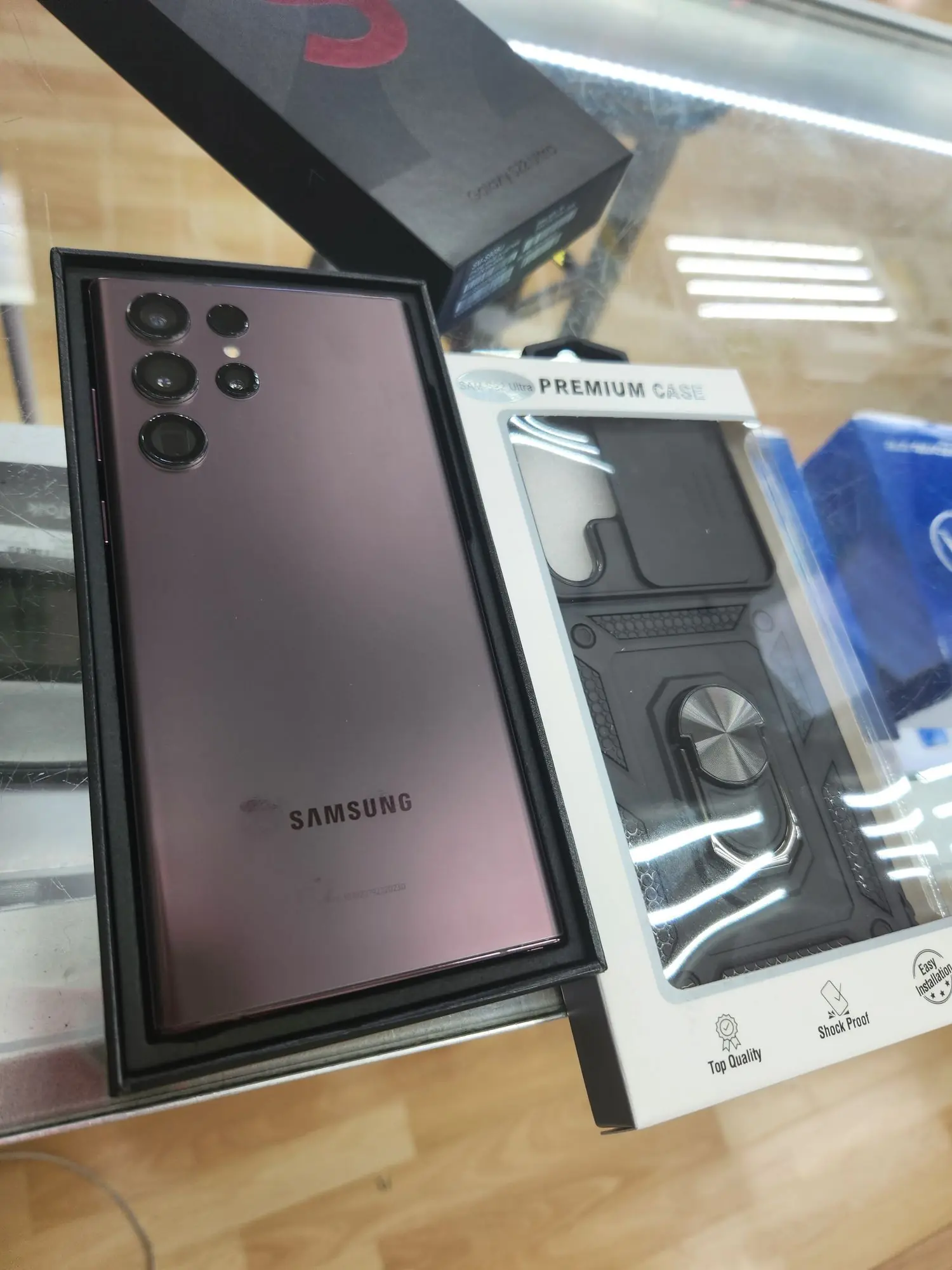 A Samsung Galaxy S22 Ultra in its box next to a rugged ring-stand case at TIC Wireless