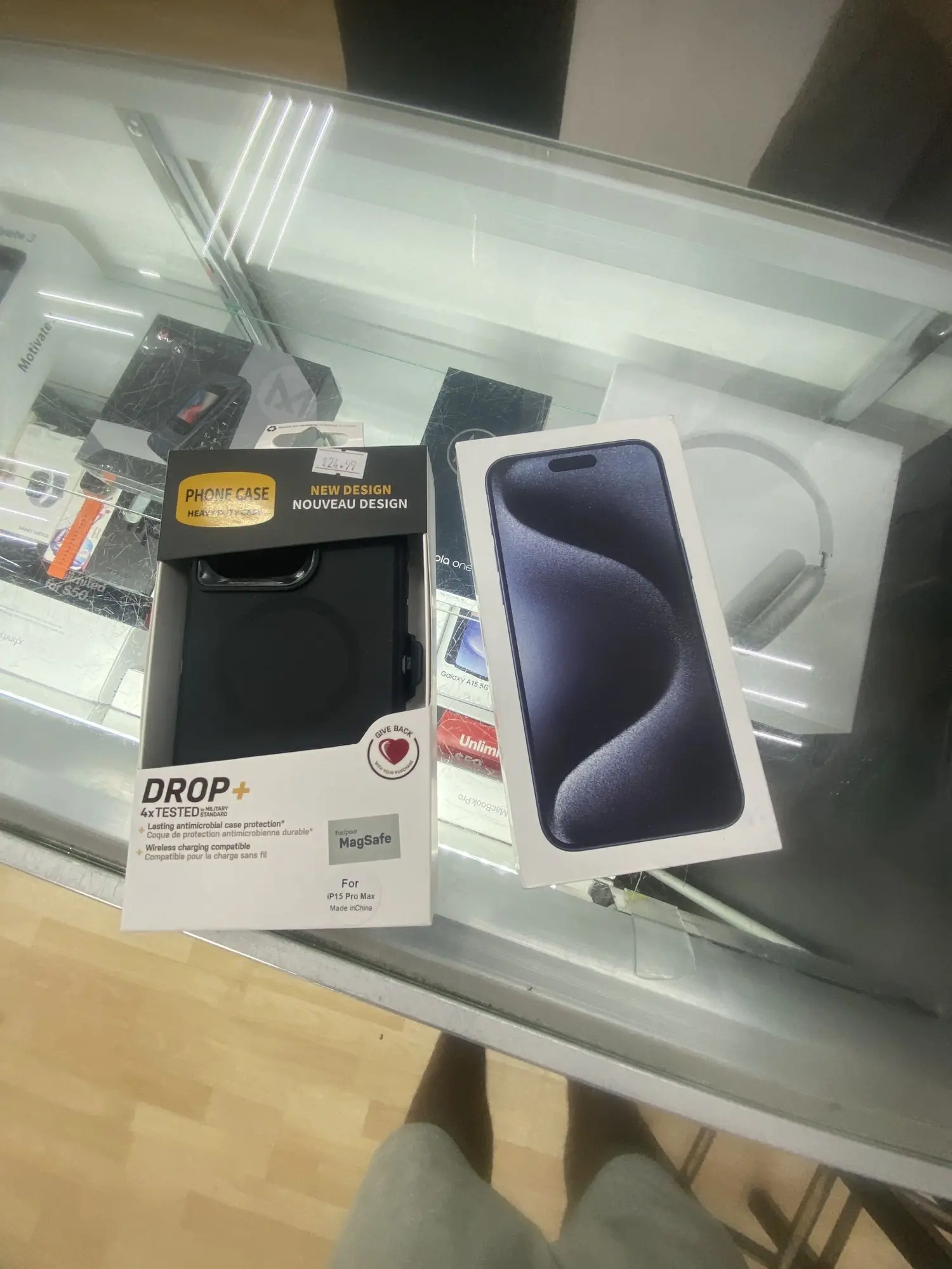 A boxed iPhone and a Drop+ MagSafe case on the display case at TIC Wireless